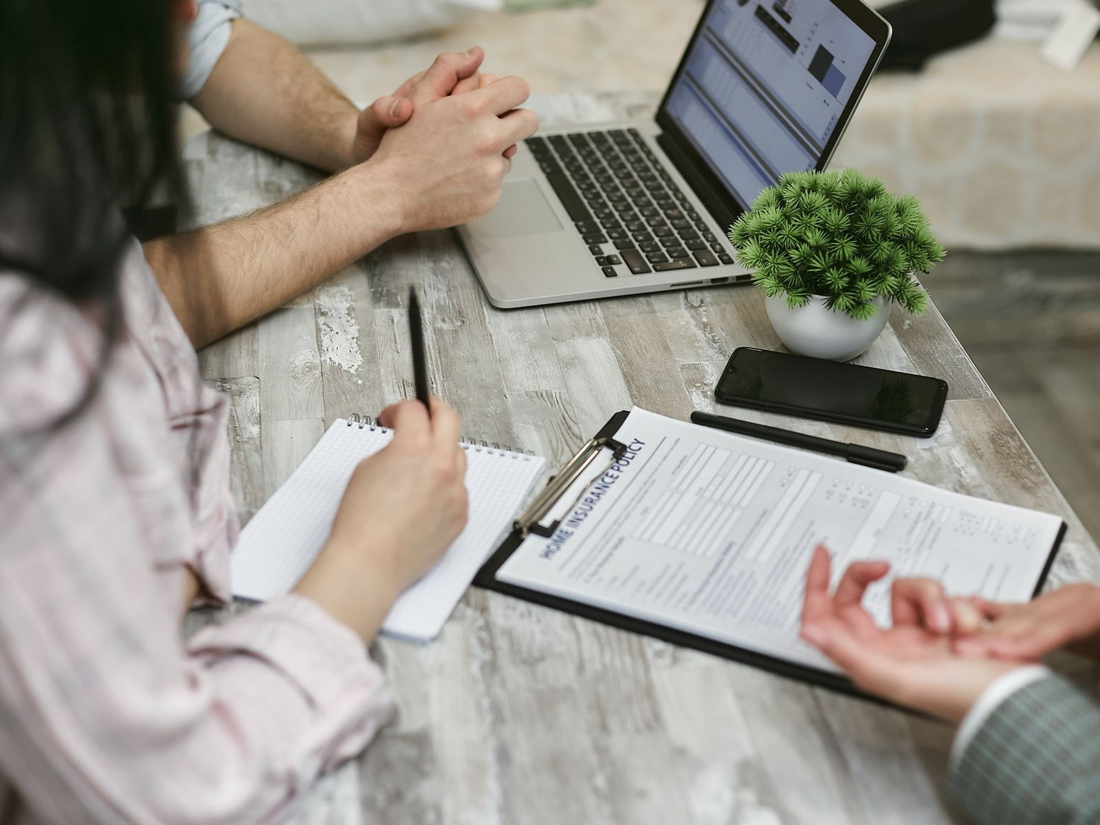 Insurance professionals reviewing policy documents and a laptop