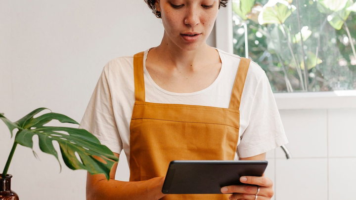 A restaurant employee using a tablet at the service counter